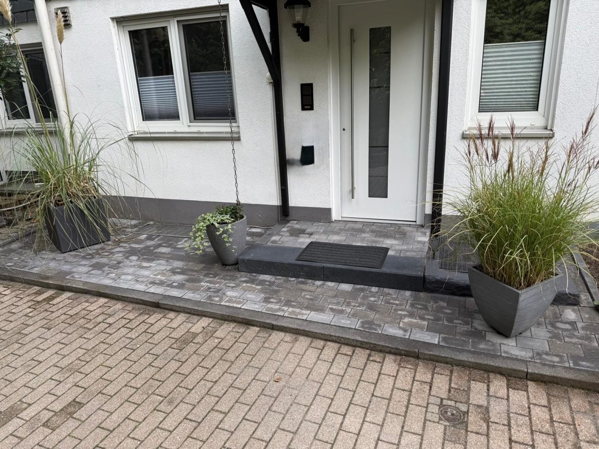 Pflasterarbeiten Langenfeld – fertiger Eingangsbereich Nachher Pflasterarbeiten Langenfeld fertiger Eingangsbereich mit grauem Pflaster und Stufe