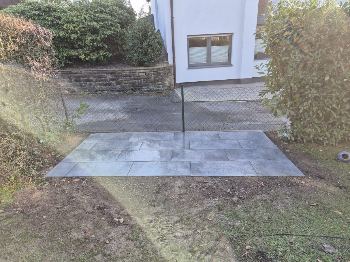 Fertige Terrasse mit grauen Pflastersteinen nach Terrassenbau und Pflasterarbeiten in Langenfeld – präzise verlegt vor weißem Haus